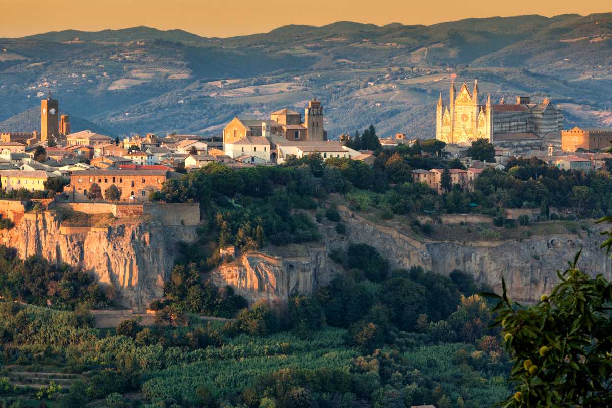Scorcio di una tavola imbandita con piatti tipici umbri, bicchieri di vino Orvieto DOC, e sullo sfondo la città di Orvieto