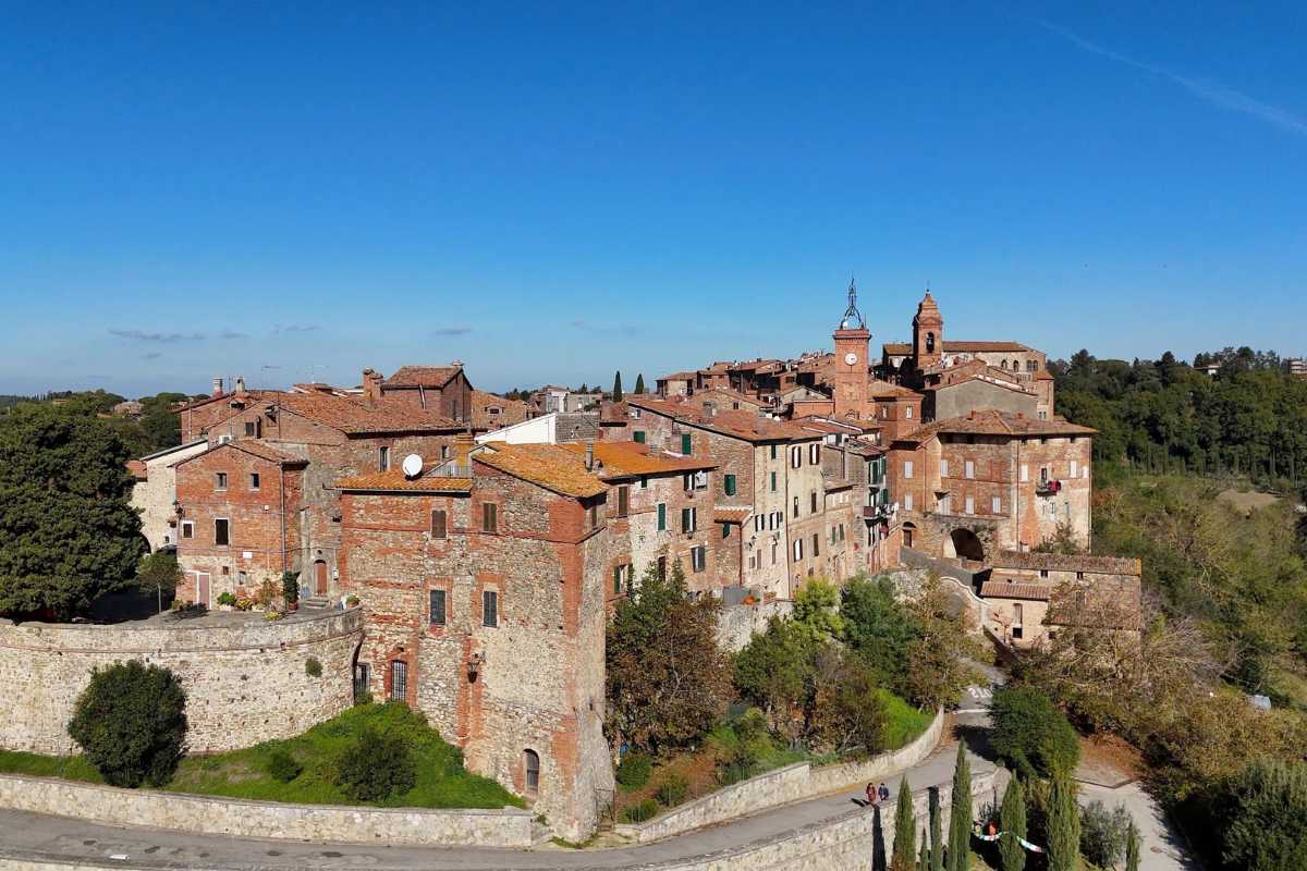 Panoramica di una piazza di Orvieto durante una festa tradizionale, con bancarelle, folla festosa, bandiere colorate e il Duomo sullo sfondo