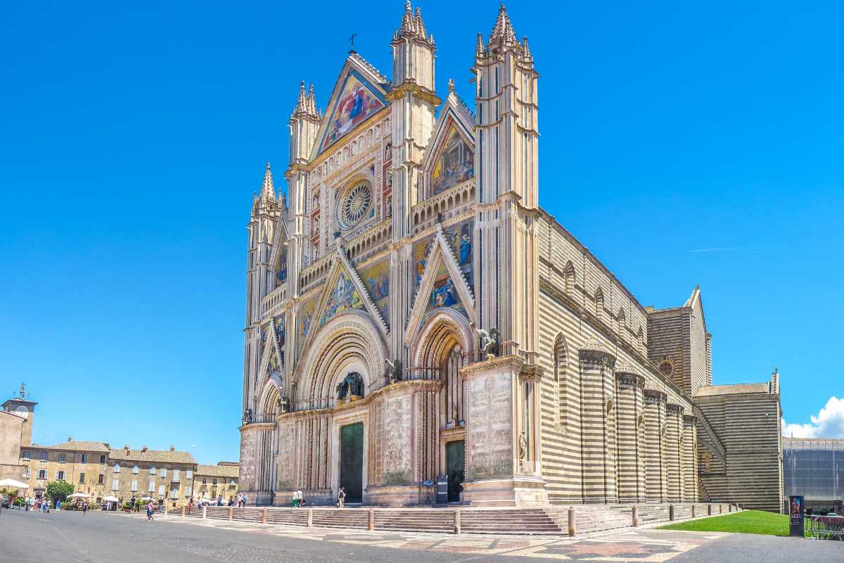 Famiglia con bambini piccoli che passeggia lungo il centro storico di Orvieto, Duomo sullo sfondo, atmosfera serena e accogliente